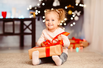 Curious little girl opening xmas gift at home