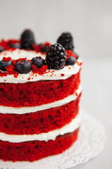 Wall Mural - homemade red velvet cake decorated with berries on a light wooden background