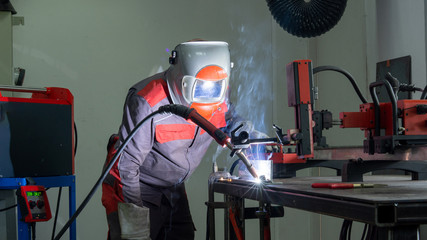 Poster - Welder working on metal pipes with sparkles in factory.
