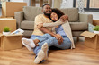 © Syda Productions - moving, repair and real estate concept - happy african american couple with cardboard boxes hugging at new home