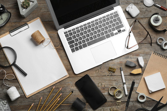 Flat lay composition with laptop, smartphone and stationery on wooden table. Designer's workplace