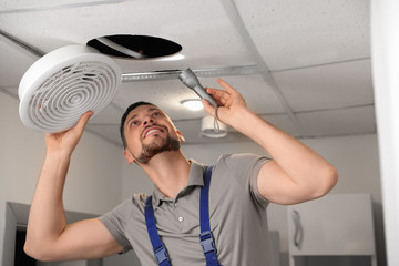 Poster - Repairman with flashlight fixing ventilation system indoors