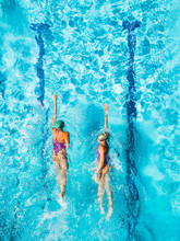 Two Women Is Swimming In A Pool, Seen From Above. She Looks Tiny In The Huge Pool.
