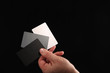 © volke - Grey Card. Set of white, black and 18% gray color cards for digital white balance adjustment in a male arm on black background. Photographer's stuff.