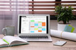 © New Africa - Laptop with calendar on wooden table in office