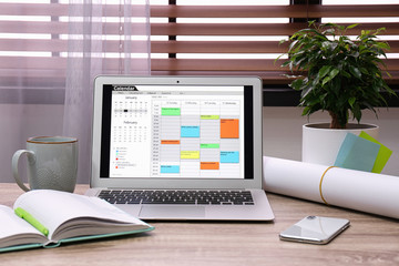 Laptop with calendar on wooden table in office