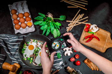 Wall Mural - Hands taking photo a delicious breakfast or snack on dark background with smartphone