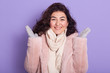 © sementsova321 - Portrait of beautiful smiling model with dark wavy hair wearing pale pink faux fur coat, gloves and scarf, female spreads palms aside, model looking at camera with charming smile. Eco furs concept.