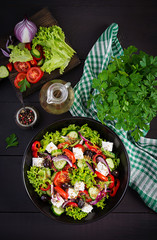 Healthy food. Greek salad with cucumber, tomato, sweet pepper, lettuce, red onion, feta cheese and olives.  Top view, copy space