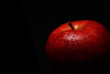Appetizing Red Apple Covered With Drops Of Water On A Black Background. Close-up