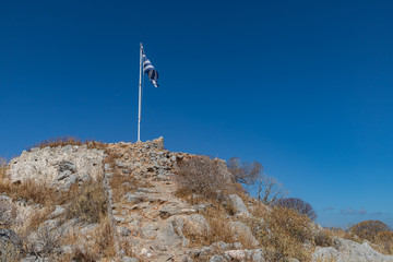 Wall Mural - Greek flag and ruins over a mountain in Hydra Island