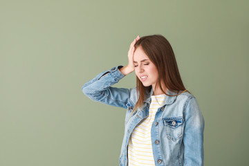 Wall Mural - Young woman suffering from headache on color background