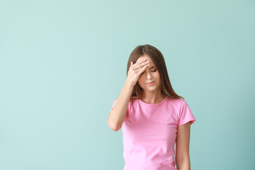 Wall Mural - Young woman suffering from headache on color background