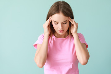 Wall Mural - Young woman suffering from headache on color background