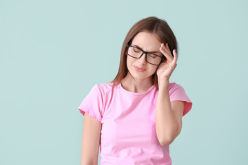 Wall Mural - Young woman suffering from headache on color background