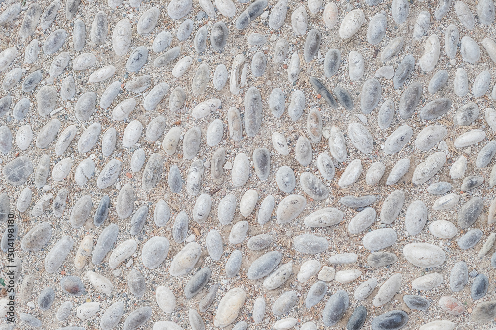 White pebble in concrete path. Top view stone background. Seaside pebble photo texture. Stone paving surface. White marbles flat lay background. Natural outdoor decor material.rounded cobbles set into
