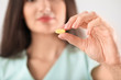 © Pixel-Shot - Young woman with pill on light background, closeup