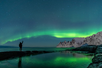 man watching the northern lights, aurora borealis, devil teeth mountains in the background, tungenes