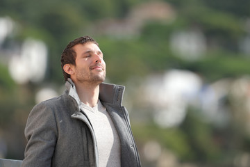 Relaxed adult man breathing fresh air outdoors in winter