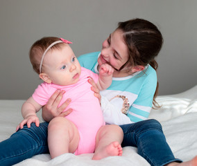 Close up Portrait of Two Sisters, Cute 8 Month Old baby Girl with Big blue Eyes and 8 Years Old School Age Girl With Brown Eyes , Happy Baby Girl