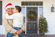 © Andy Dean - Hispanic Male Soldier Wearing Santa Cap Holding Mixed Race Son In Front of House