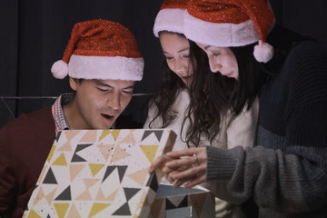 father, mother, daughter open a gift present box together at christmas day night in living room that decorated with christmas tree for christmas festival day