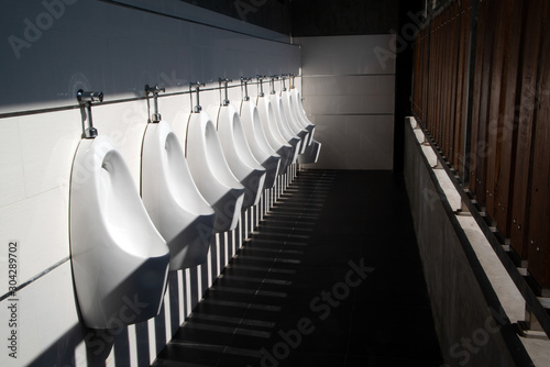 Cuadros en Lienzo Art light and shadow of men's restroom with white porcelain urinals in line