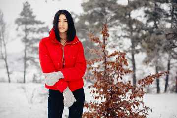 Wall Mural - Cute girl walking in a winter park. Woman in a red jacket