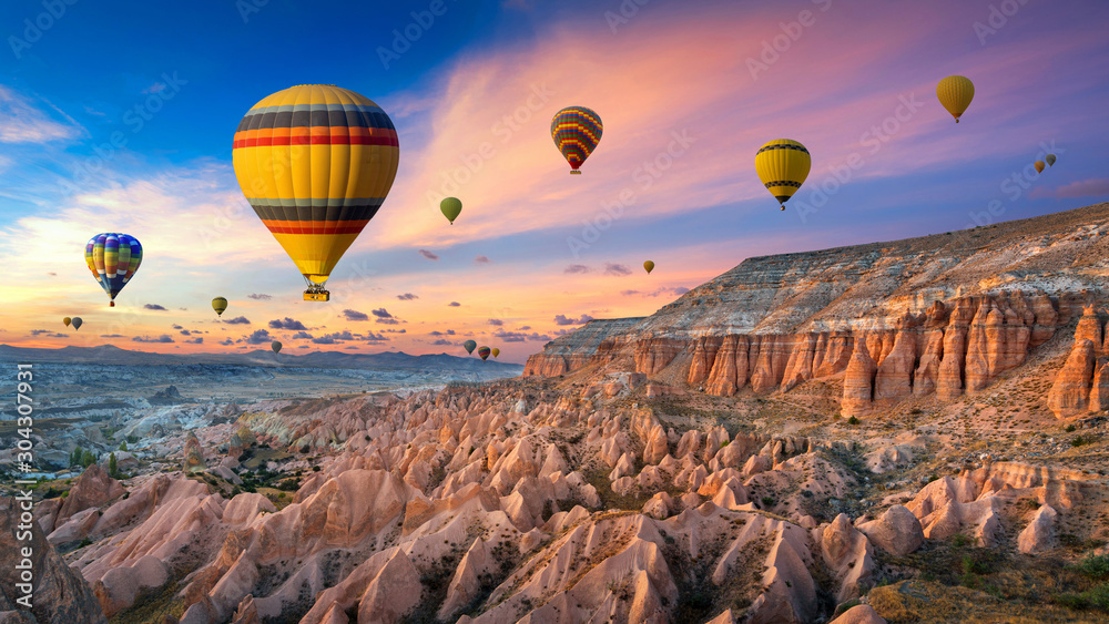 Hot air balloons and Red valley  at sunset in Goreme, Cappadocia in Turkey. - obrazy, fototapety, plakaty 