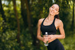 © speed300 - Sporty woman holding a bottle with water outdoor and looking at the camera. - Image