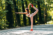 Girl  Bend Back To Leg Up And Holding By One Hand To  Leg And Other Hand Reach Forward Outdoor