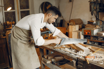 Wall Mural - Man working with a wood. Carpenter in a white shirt. Worker with a saw