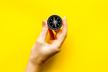 Wall Mural - Choose direction concept. Compass in hand on yellow background top view copy space