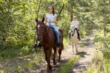 Group Of Teenagers On Horseback Riding In Summer Park