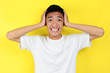 Portrait of young Asian teenager unhappy scared man, isolated on yellow