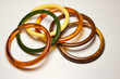 Close up view of vintage bakelite bangle bracelets in varying colors and widths on white background
