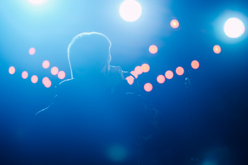 Canvas Print - Singer on a stage with microphone in a backlights 