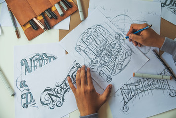 Wall Mural - Typography Calligraphy artist designer drawing sketch writes letting spelled pen brush ink paper table artwork.Workplace design studio.