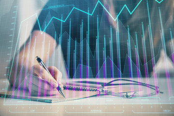 Multi exposure of woman's hands making notes with forex graph hologram. Concept of technical analysis.