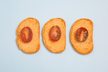 Tostadas con hummus y tomates cherry sobre fondo azul celeste.