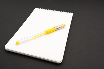 school white notebook with pen on black background