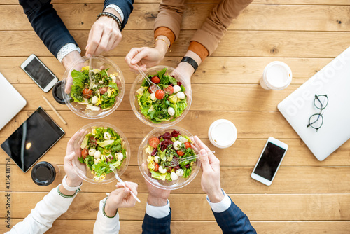 Cuadros en Lienzo Office workers during a business lunch with healthy salads and coffee cups, view