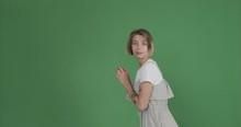 Shy Young Woman Dancing And Disappearing Over Green Background
