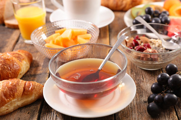 Wall Mural - bowl of tea with healthy breakfast- fruit, muesli, bread and orange juice