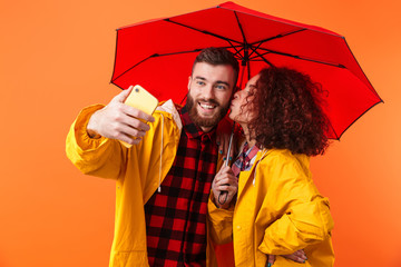 Canvas Print - Loving couple posing in yellow raincoats isolated