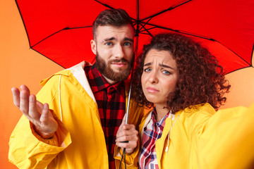 Poster - Loving couple posing in yellow raincoats isolated