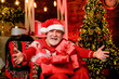 Come here. Merry christmas. Grandpa at home. Traditions concept. Santa Claus near christmas tree. Bearded senior man Santa Claus. Santa Claus relaxing in arm chair. Delivering gifts. Winter vacation