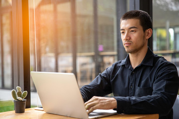 Shot of a young businessman working on his laptop in a cafe shop.