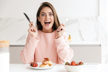 Beautiful smiling young girl having tasty healthy breakfast