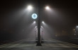 Illuminated, empty platform at a railroad station during a foggy night in autumn.